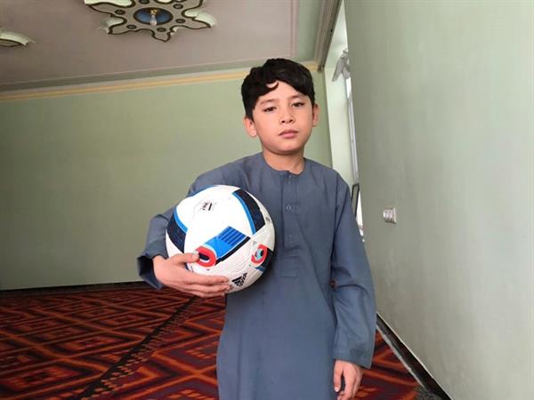 Murtaza Ahmadi sostiene un balón de fútbol al interior de su casa